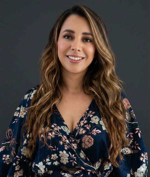 A lawyer Woman wearing a floral dress against a dark background She is the author of the book "A puerta Cerrada, Acoso sexual y Laboral"